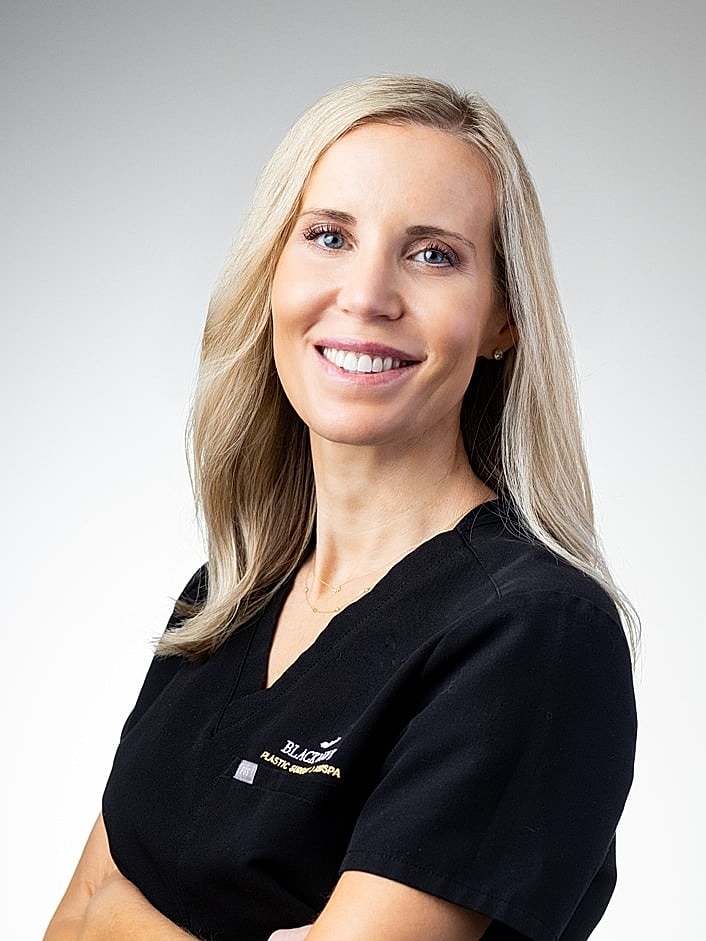 Smiling healthcare professional in black scrubs.