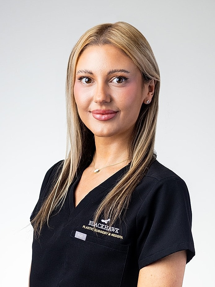 Professional woman wearing scrubs, smiling.