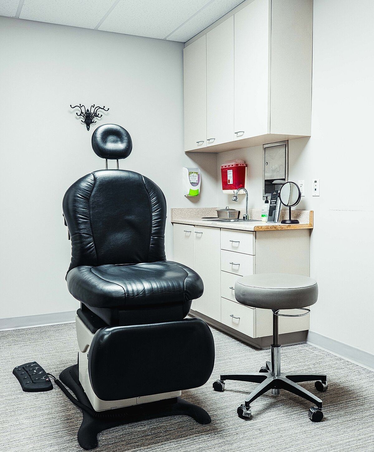 Medical examination room with chair and supplies.