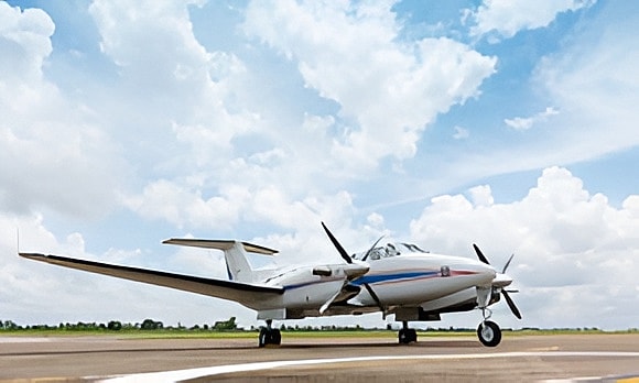 Small aircraft on runway under cloudy sky.