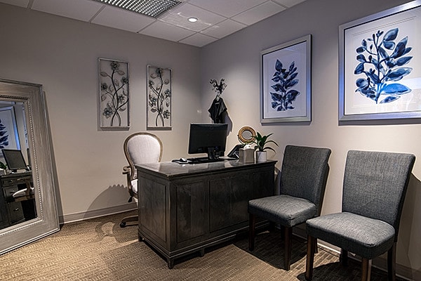 Blackhawk Plastic Surgery consultation office with desk, chairs, and botanical artwork