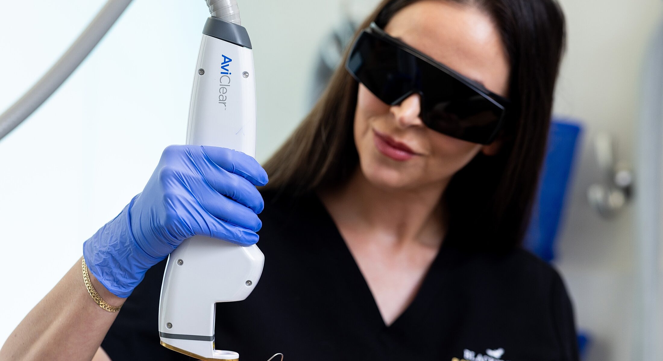 Professional using AviClear laser treatment device.