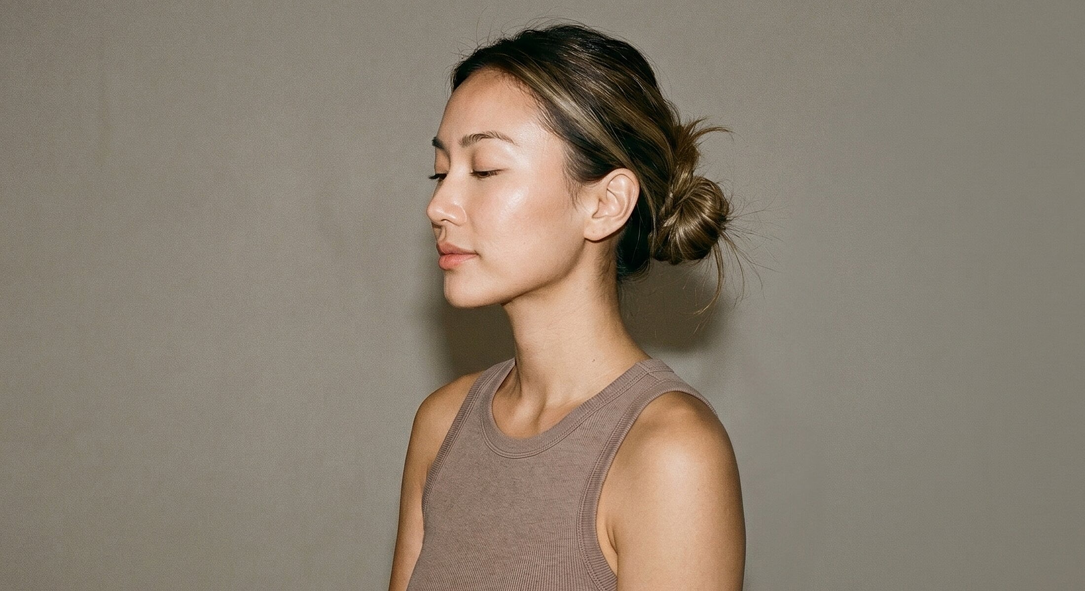 Woman with bun hairstyle against a neutral background.