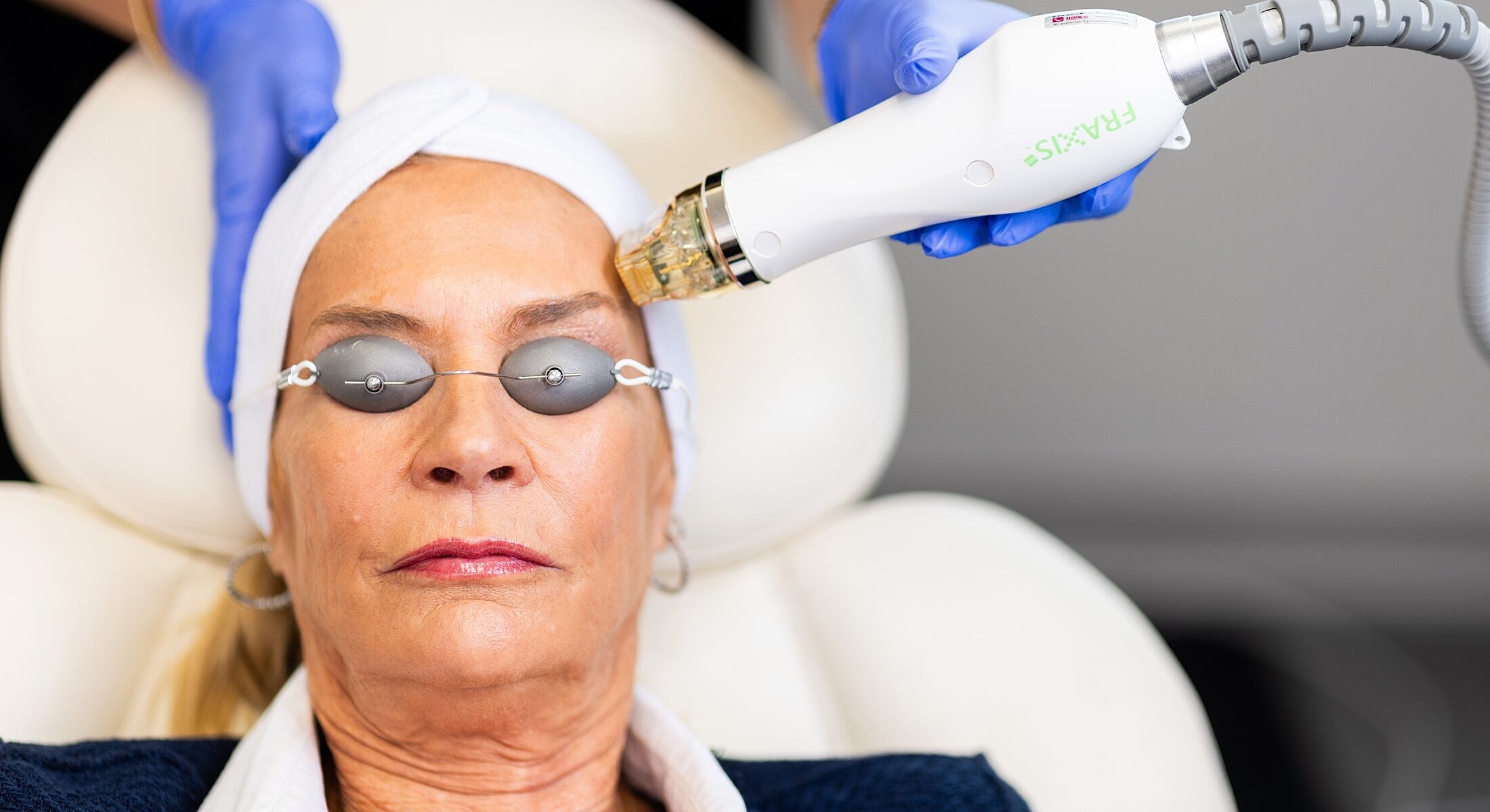 Woman receiving facial treatment with laser device.
