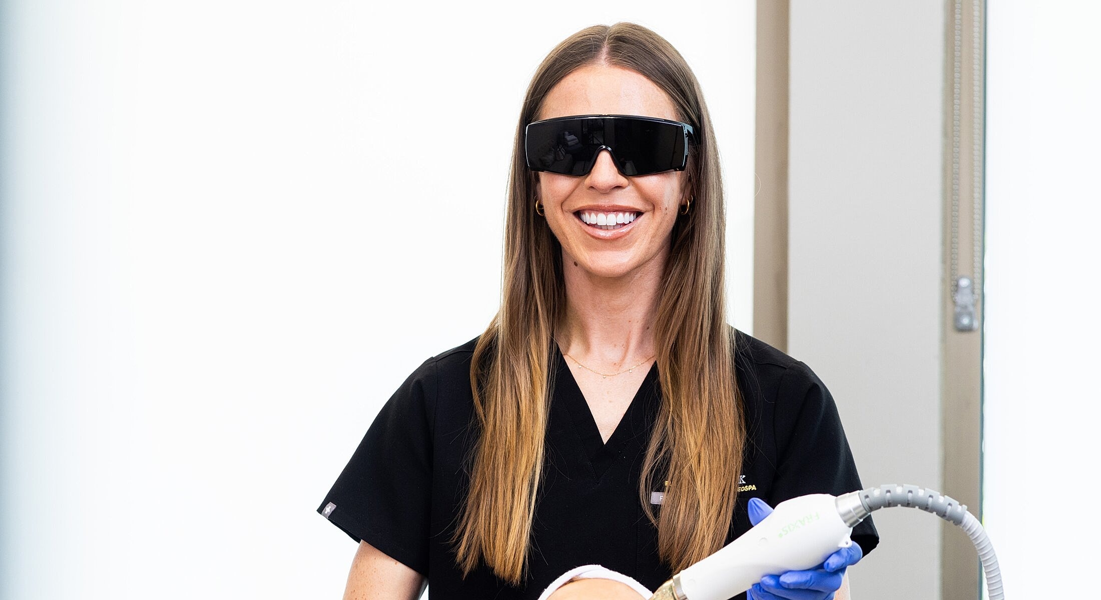 Medical professional holding a laser tool, smiling.