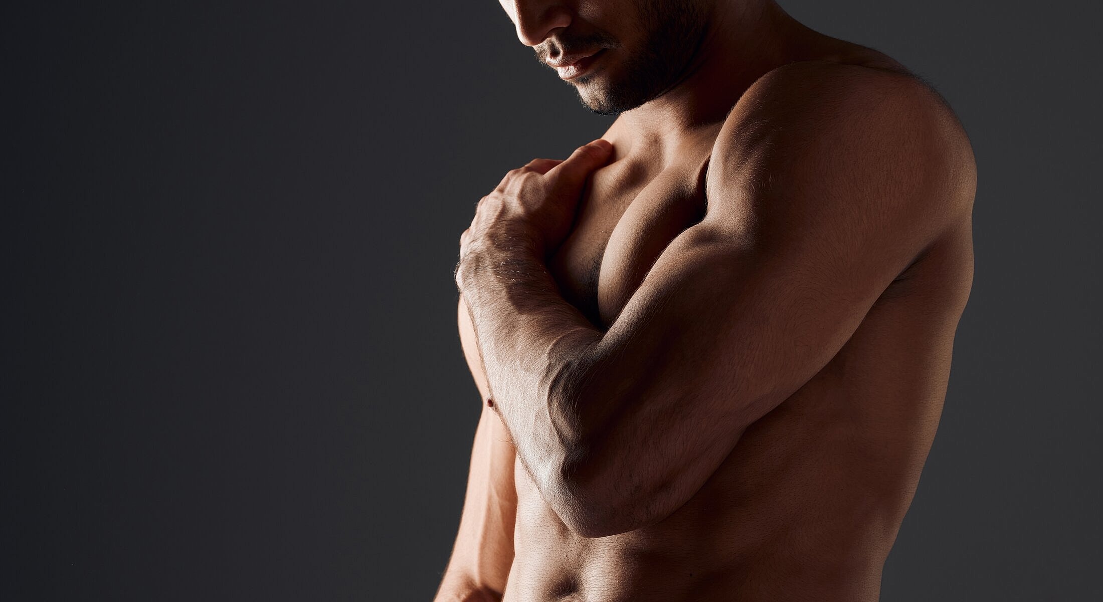 Athletic man poses showcasing muscular physique.