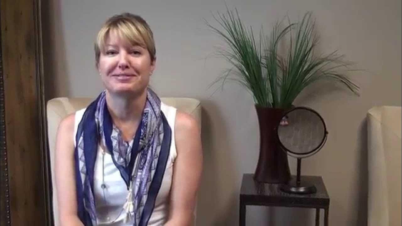Woman sitting with a decorative plant backdrop.